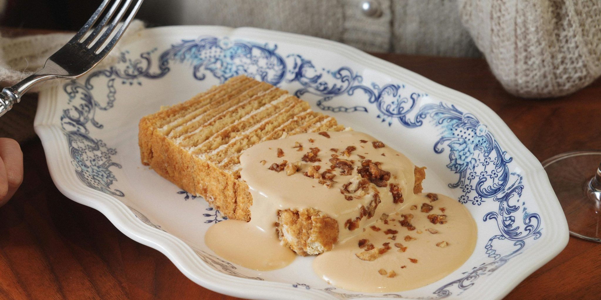 A slice of layered cake with cream sauce elegantly presented on a decorative plate.